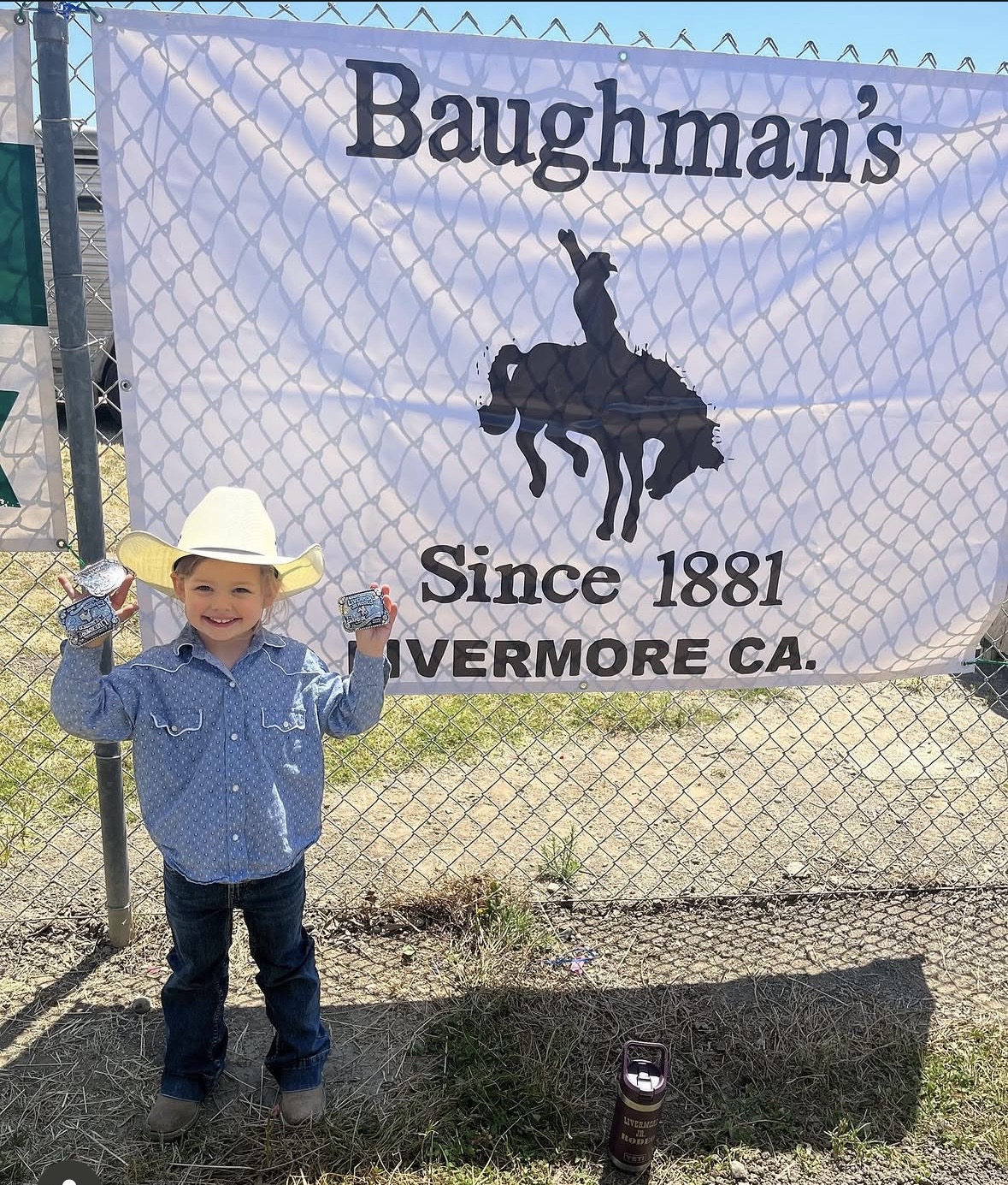 Young customer holding rodeo buckles in front of the Baughman's Since 1881 banner