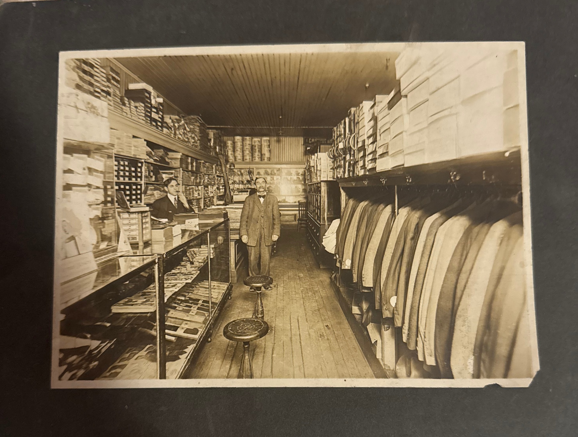 Original Baughman's storefront interior, sepia photograph with the proprietor standing in the aisle