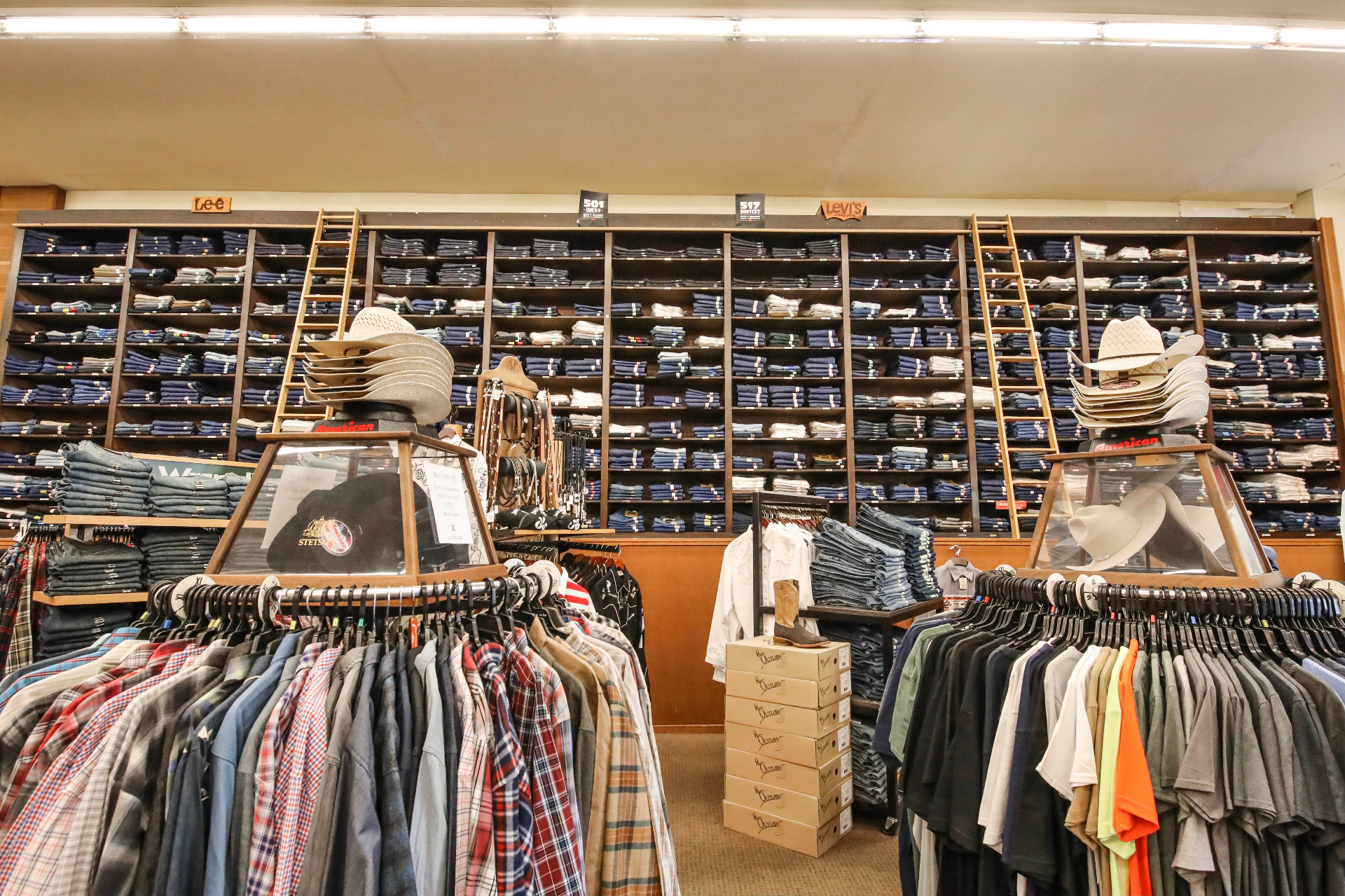 Floor-to-ceiling wall of folded Levi's, Lee, and Wrangler denim with rolling ladders