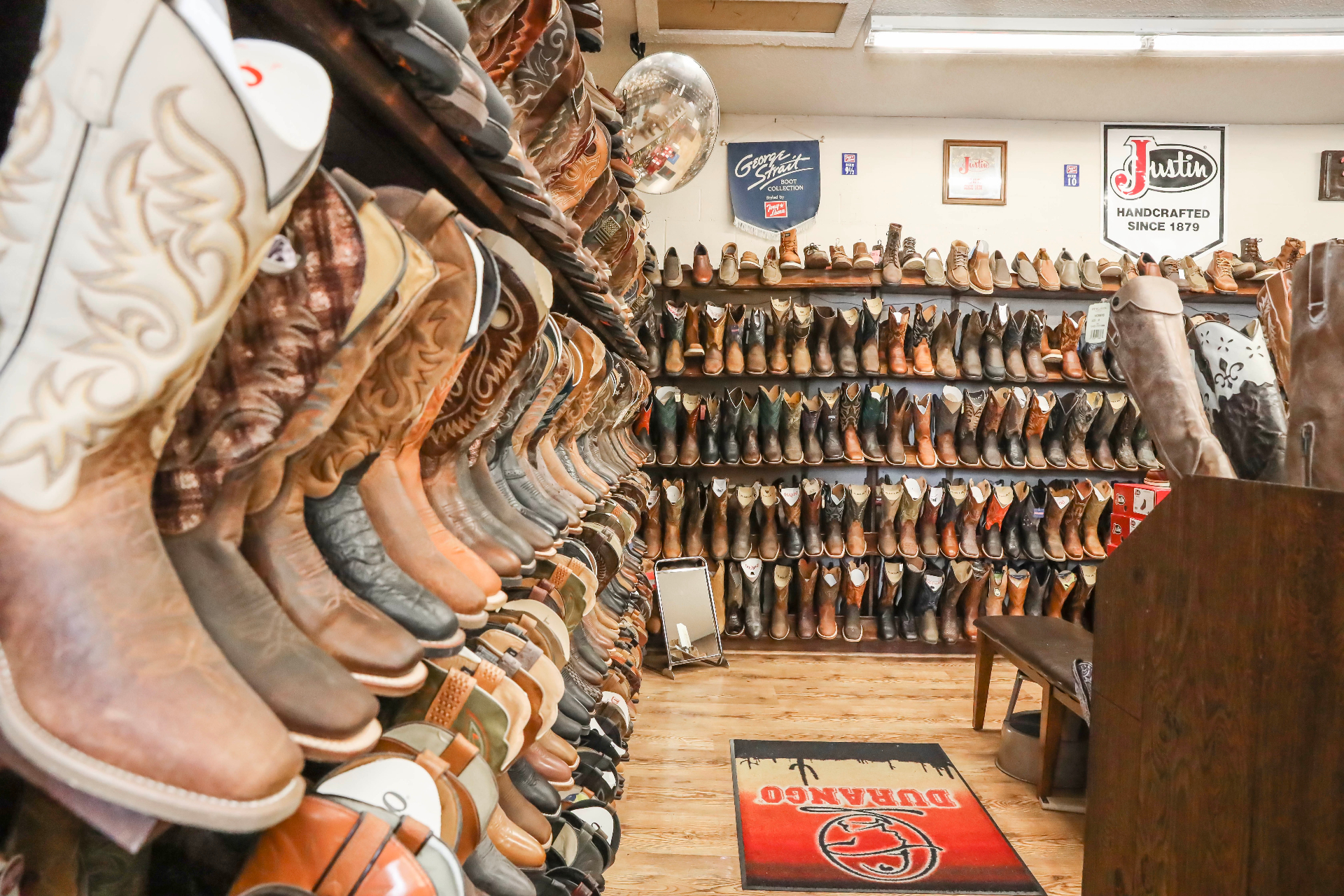 Aisle of cowboy boots lining both walls, Justin and George Strait collections on display